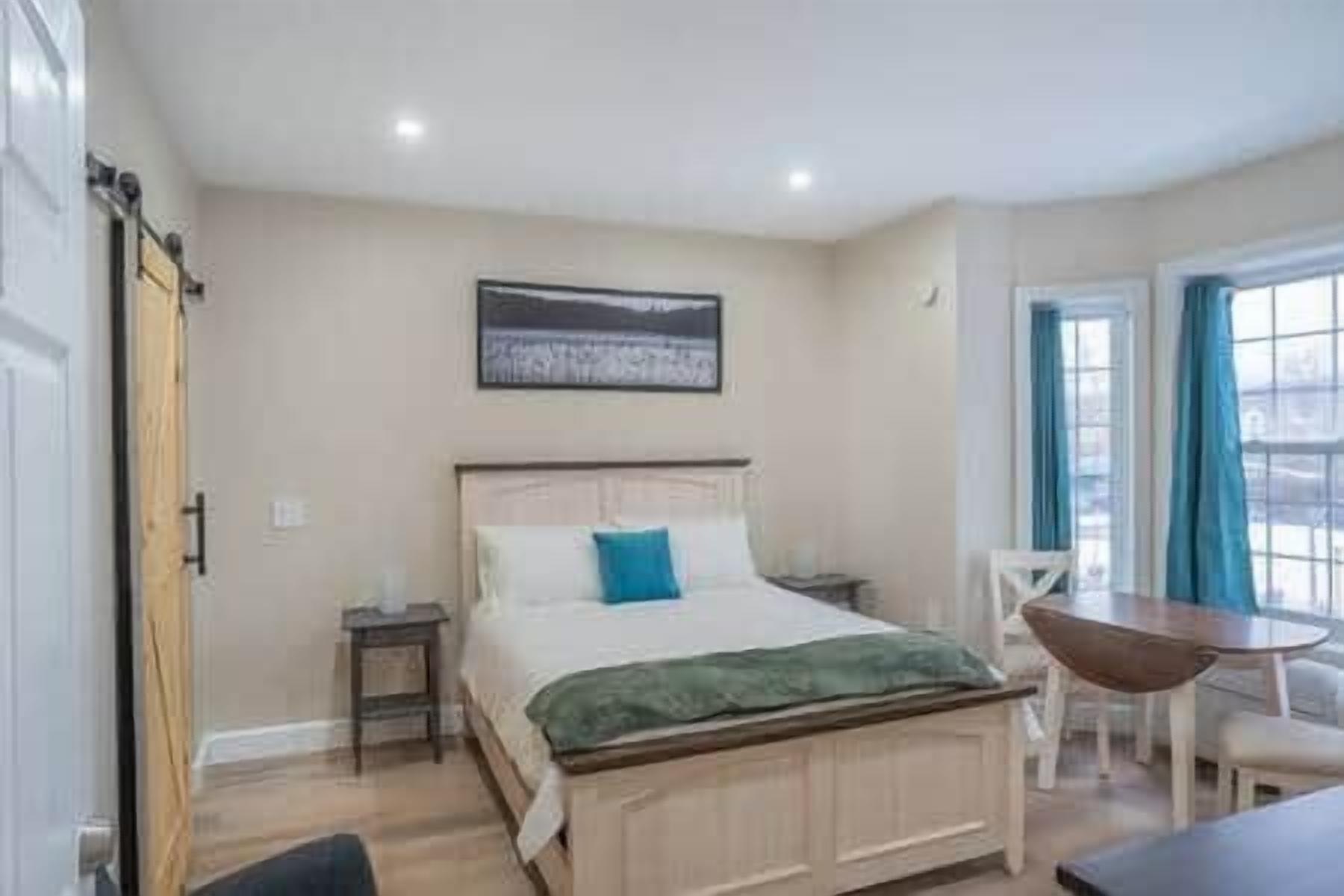 Quarto com cama, mesas de cabeceira, uma cadeira e uma mesa.