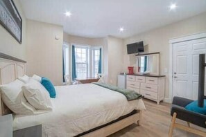 A bedroom with a bed, bedside table, dresser, and a television.