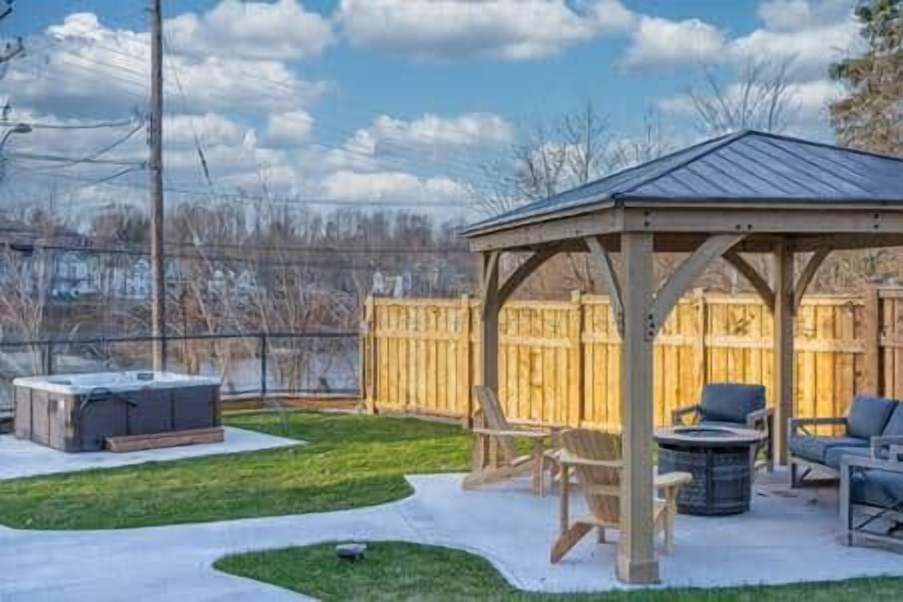 Un espace extérieur aménagé avec une structure en bois, abrité et doté d’un coin salon, d’un jacuzzi et d’un barbecue.