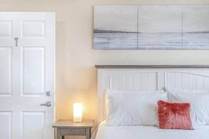 A bedroom with a white bed, a nightstand, a lamp, and a painting on the wall. - Riverside Inn - Unit 7 (New Glasgow)
