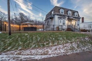 A two-story house with a front porch, a staircase, and a fenced yard. - Riverside Inn - Unit 7 (New Glasgow)
