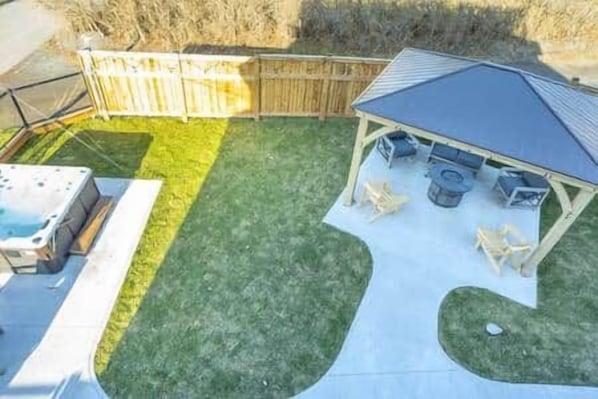 A backyard with a hot tub, a covered patio area, and a wooden fence. - Riverside Inn - Unit 7 (New Glasgow)