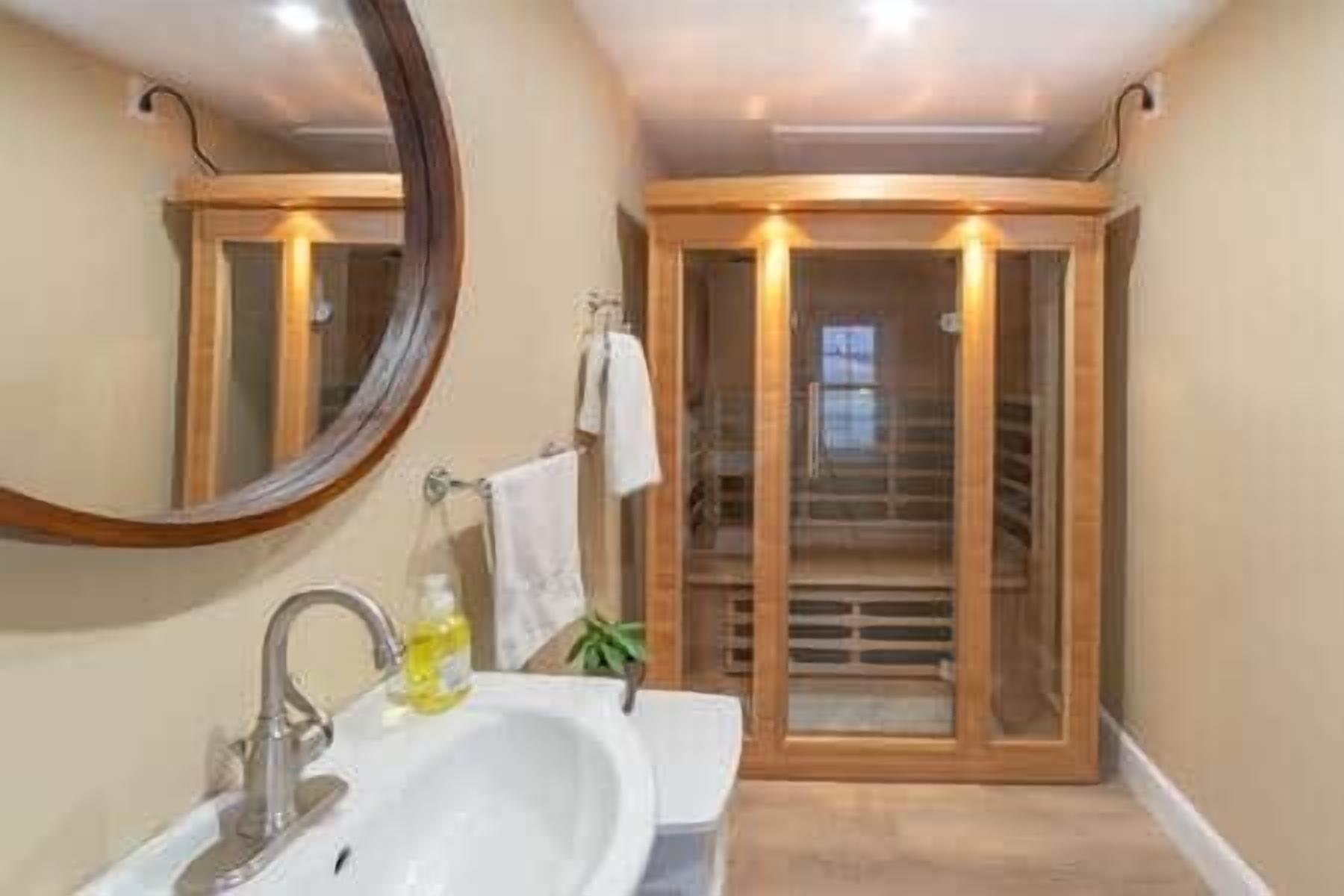 Un baño con lavamanos, espejo y cabina de ducha de madera.