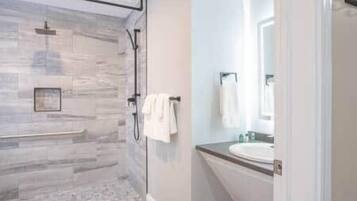 Une salle de bain moderne avec une douche à parois de verre, un meuble-lavabo et un porte-serviettes.