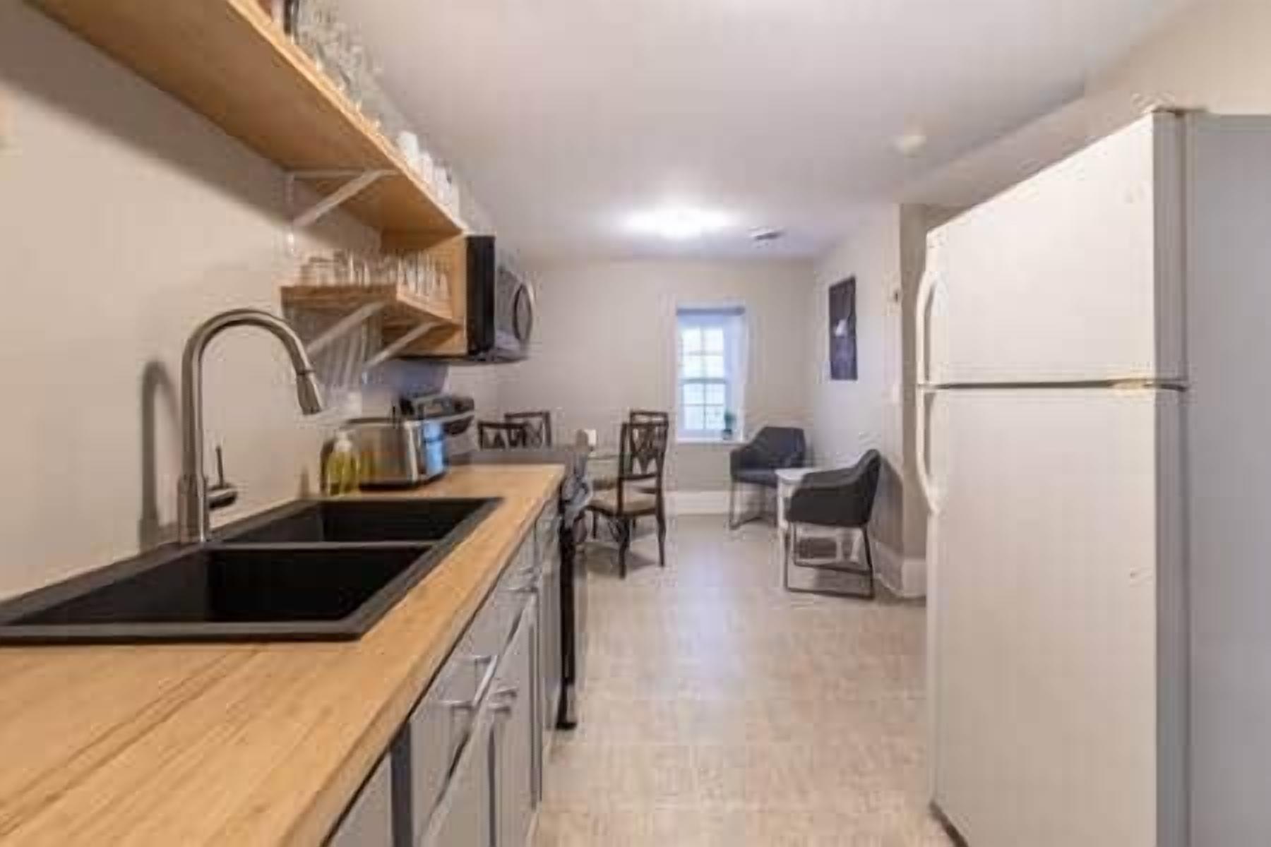A kitchen with a wooden countertop, a sink, and a refrigerator.