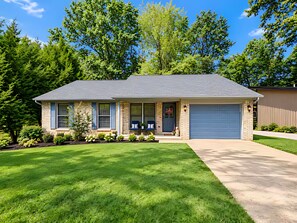 A two-story residential house with a front porch, a garage, and a well-maintained lawn.
