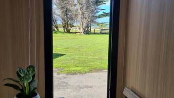 A room with a view of a grassy area and trees through an open door.