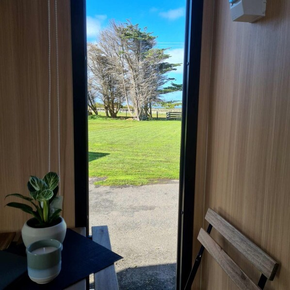 A room with a view of a grassy area and trees through an open door.
