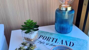 Una mesa con una botella azul, un pequeño terrario de cristal, una tarjeta con la inscripción 'PORTLAND life is beautiful' y dos bombones.