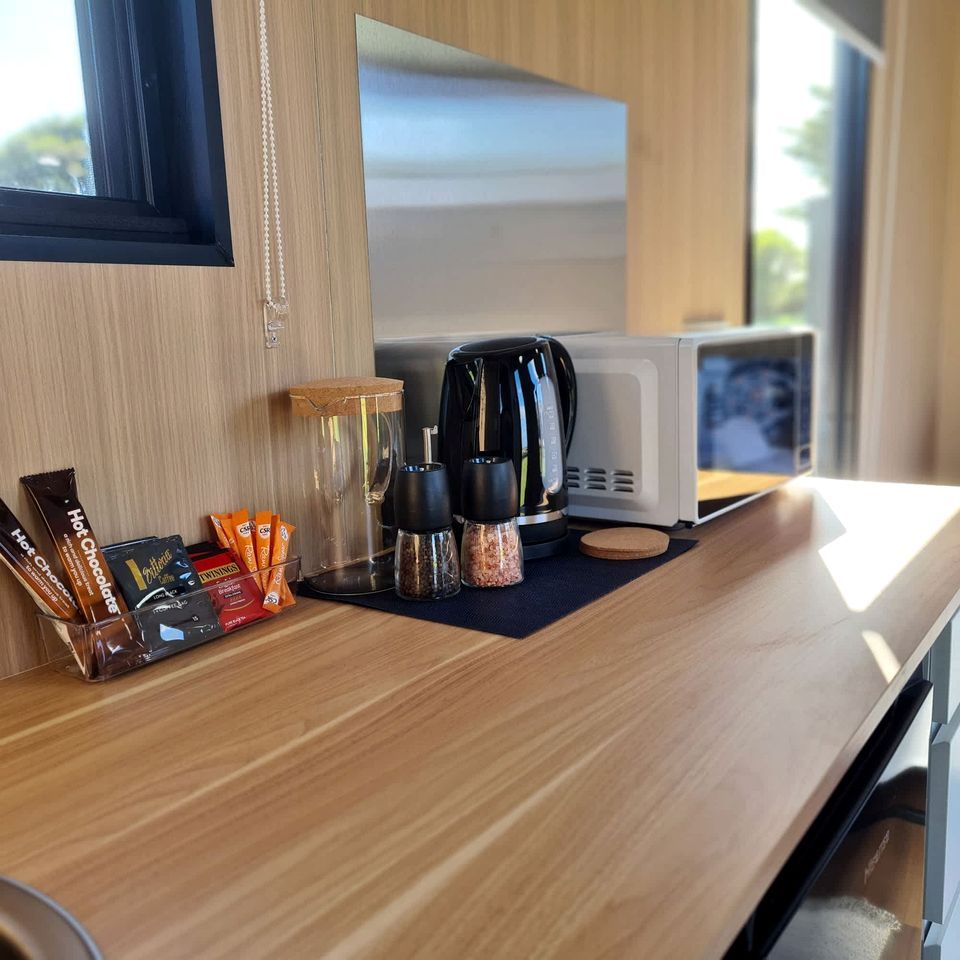A kitchen counter with a coffee maker, salt and pepper shakers, and a microwave.