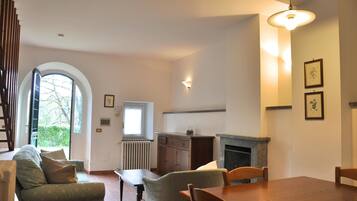 A dining area with a fireplace, a window with blinds, and a radiator.