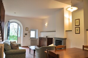 A dining area with a fireplace, a window with blinds, and a radiator. - Montecasciano Rosa (Capranica)