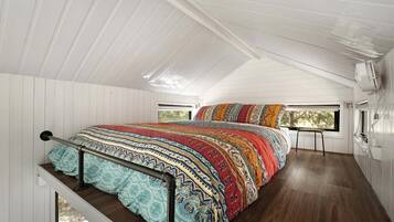 Une chambre avec un grand lit, une fenêtre et un plancher en bois.