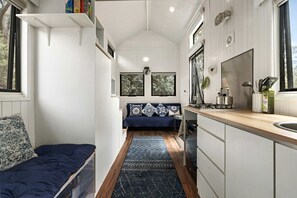 A narrow, compact kitchen with a built-in stove, a sink, and a window above the sink.