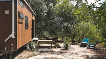 En campingvogn med terrasse, udendørs møbler og en lille have.
