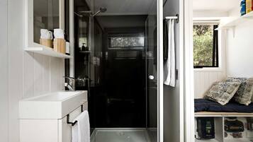 Une petite salle de bain avec une douche, un lavabo blanc et un porte-serviettes.