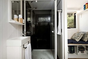 A compact bathroom with a shower, a white sink, and a towel rack.