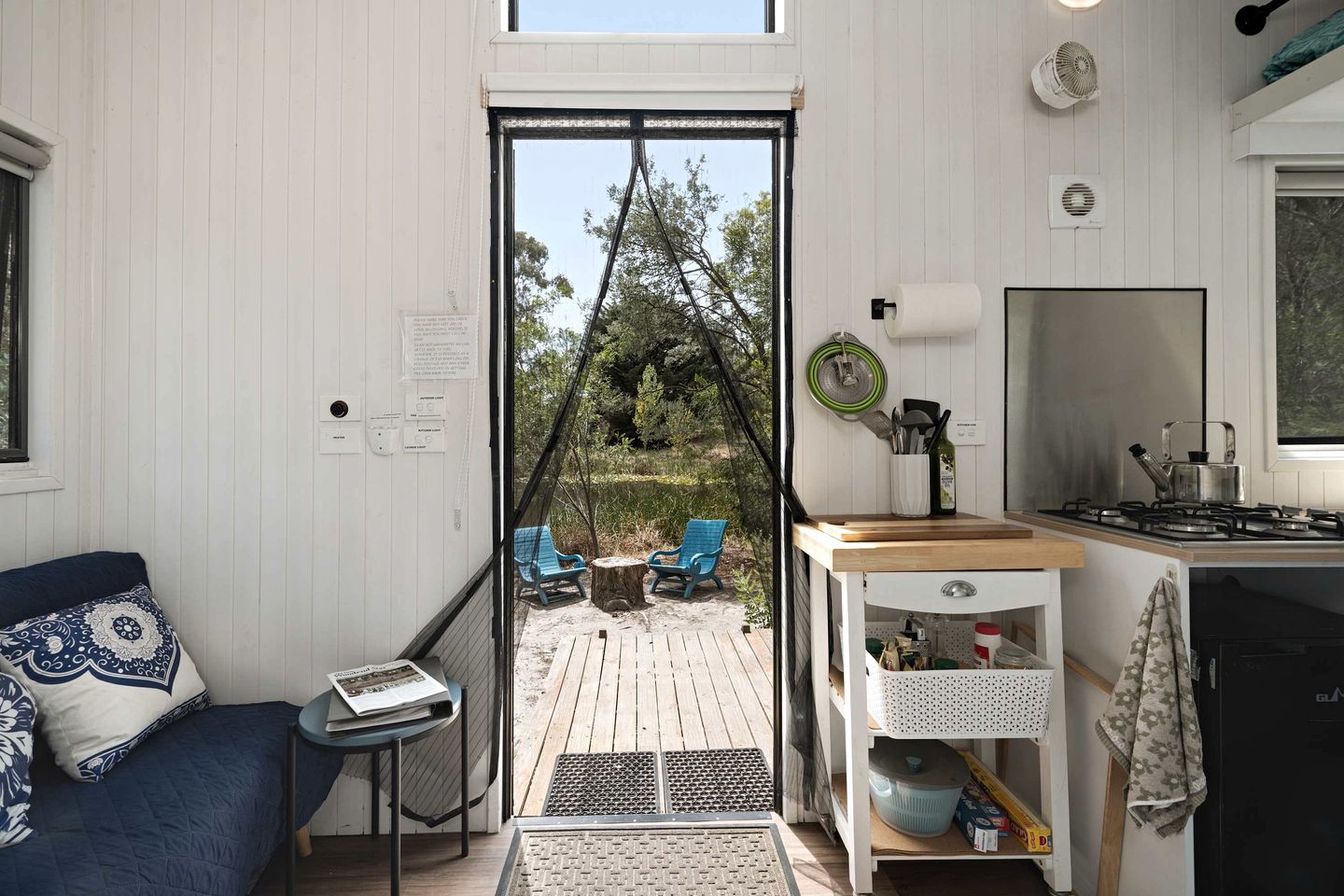 A compact living space with a kitchenette, a dining area with outdoor seating, and a view of the surrounding landscape.