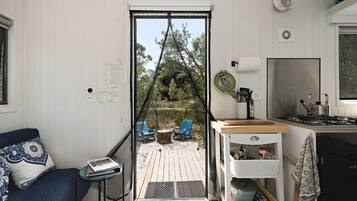 A compact living space with a kitchenette, a dining area with outdoor seating, and a view of the surrounding landscape.