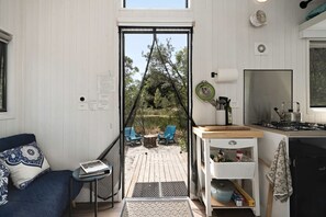 A compact living space with a kitchenette, a dining area with outdoor seating, and a view of the surrounding landscape.