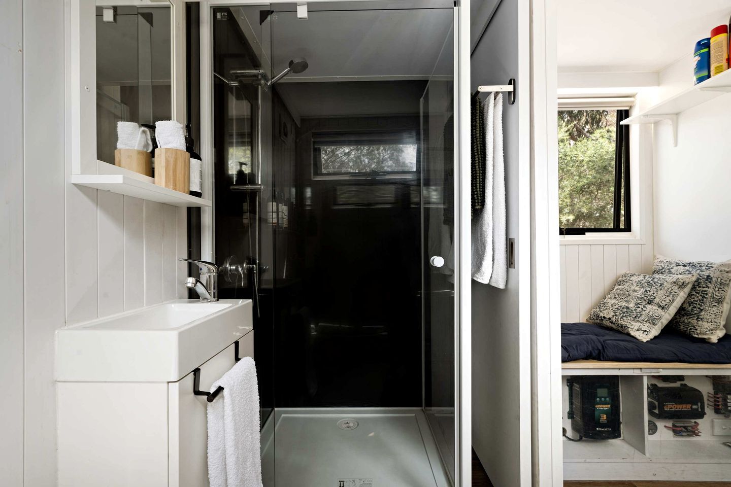 Une petite salle de bain avec une douche, un lavabo blanc et un porte-serviettes.