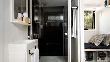 Une petite salle de bain avec une douche, un lavabo blanc et un porte-serviettes.