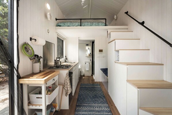 A compact kitchen with a built-in stove, wooden counter, and a small dining area.