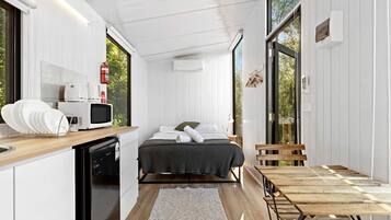 Une pièce compacte comprenant un lit, une petite kitchenette et un coin repas.