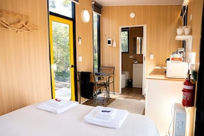 A room with a bed, a desk, and a chair, with a view of the outdoors.