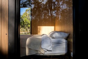 A room with a bed, a window, and a view of trees.
