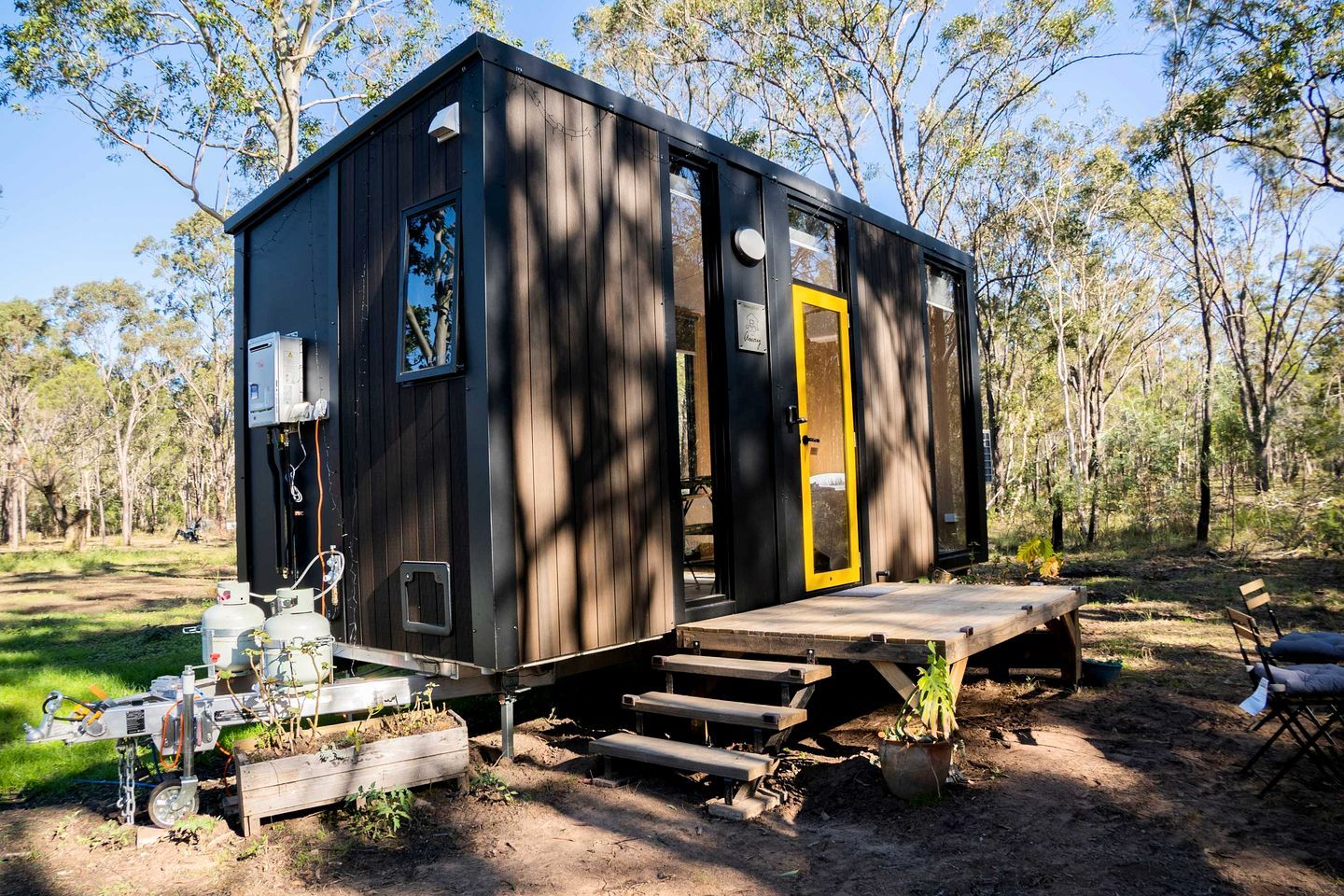 A small cabin with a wooden deck, a yellow door, and a window.