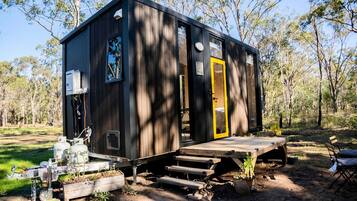 A small cabin with a wooden deck, a yellow door, and a window.