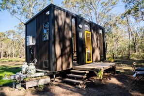 A small cabin with a wooden deck, a yellow door, and a window.