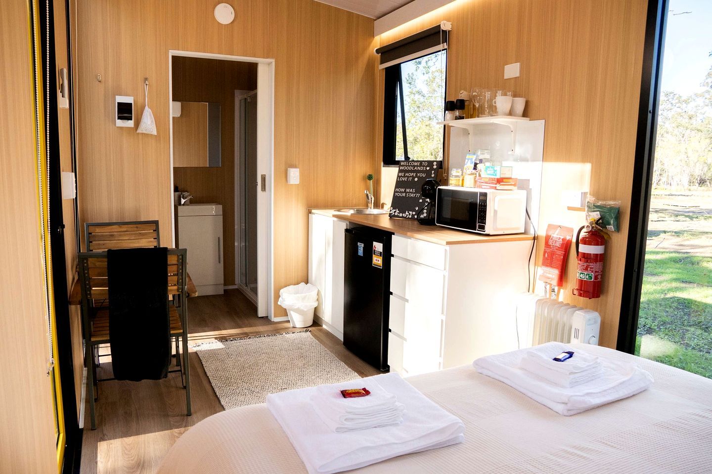 A compact room with a bed, a small kitchenette, a bathroom, and a view of the outdoors.