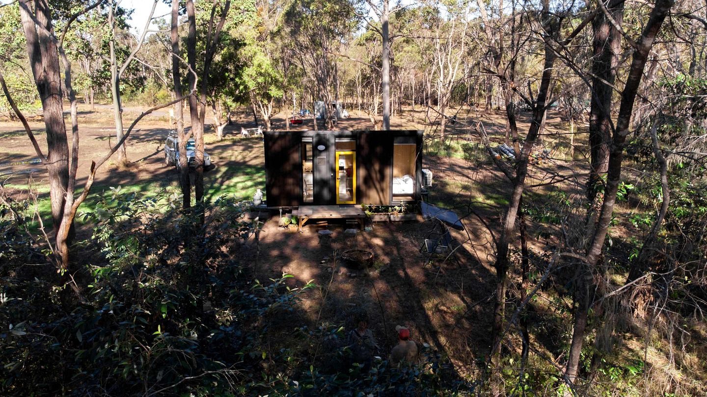 A small, enclosed structure with a door and windows, surrounded by trees and vegetation.