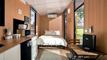A compact room with a bed, a small table, a chair, a microwave, and a sink.