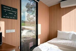 Una habitación moderna con cama, una señalización y vistas a través de una puerta de cristal.