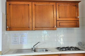 A kitchen with wooden cabinets, a stainless steel sink, and a gas stove. - Montecasciano Girasole (Capranica)