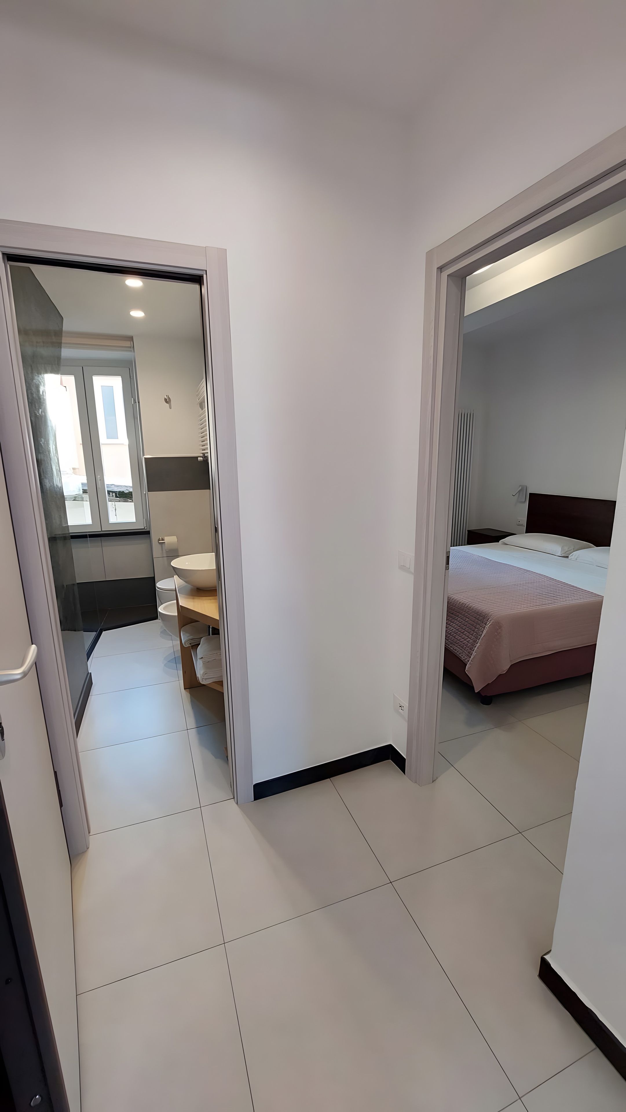 Ett hotellrum med en säng, ett sängbord, ett badrum med toalett och handfat samt en dusch.
