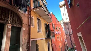 En smal gata med byggnader på båda sidor, balkonger där kläder hänger och en gatlykta i gammaldags stil.