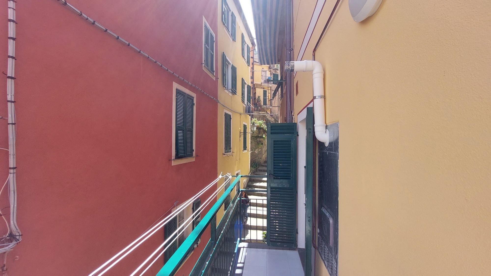 Une ruelle étroite, située entre deux bâtiments, avec un escalier menant à un niveau supérieur.