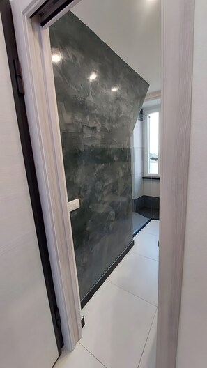 Ein modernes Interieur mit einer großen, dunkel gefärbten Wand, einer weißen Tür und einem gefliesten Boden.