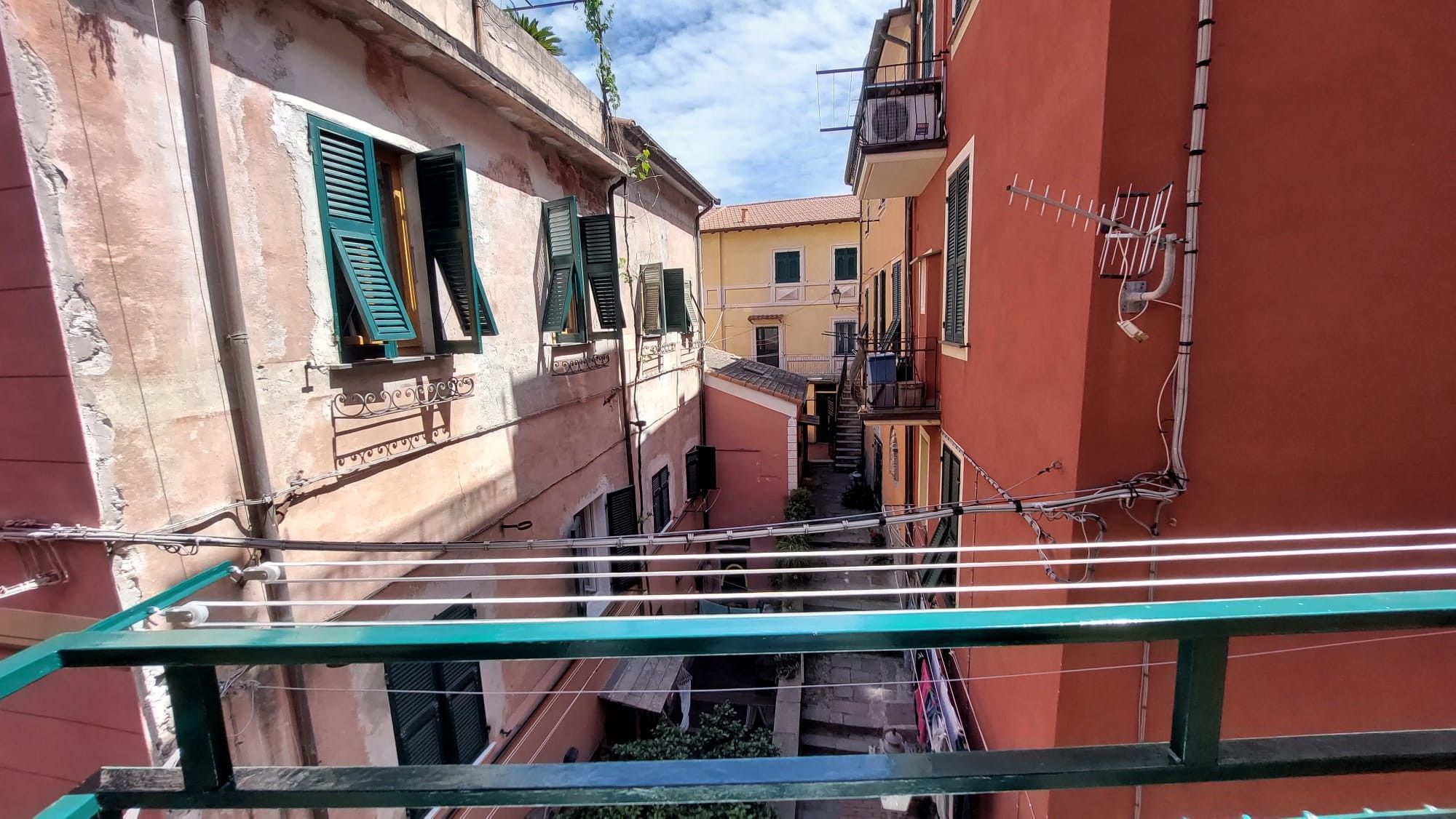 En smal stadsgata med byggnader, balkonger och elledningar som hänger ovanför gatan.