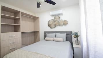 A bedroom with a bed, a wardrobe, a ceiling fan, wall art, and a window with curtains.