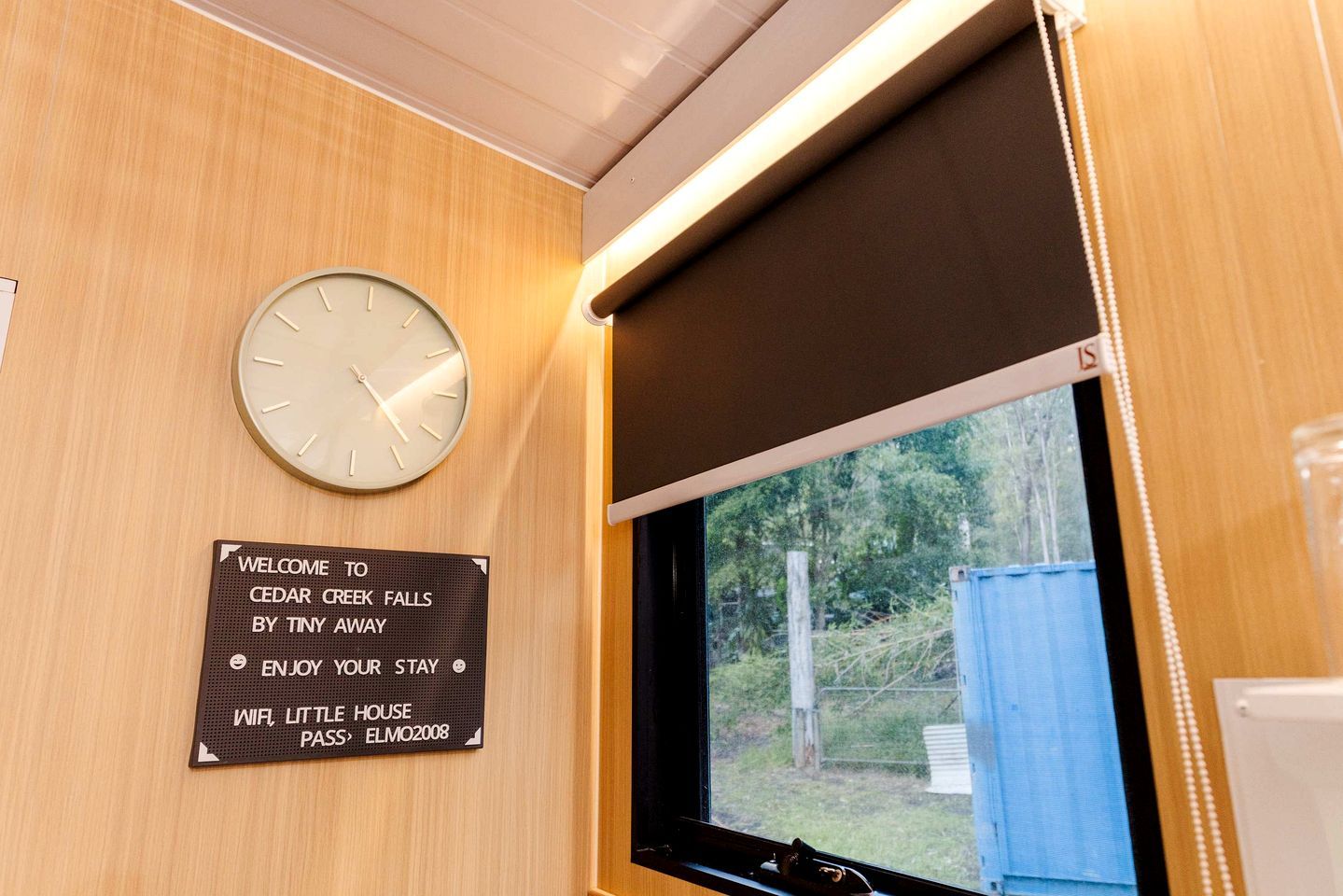 Une horloge, une pancarte de bienvenue et une fenêtre donnant sur un paysage verdoyant.