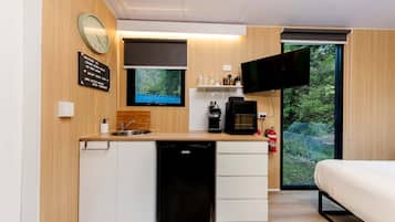 A compact kitchenette with a sink, coffee maker, and a flat-screen TV.