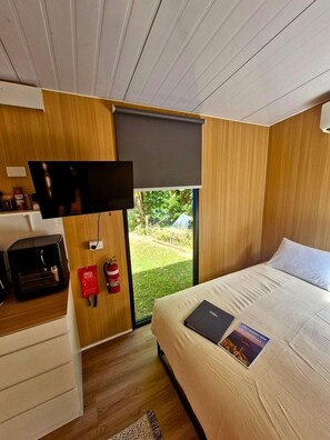 A modern bedroom with a bed, a television mounted on the wall, and a small desk with a computer.