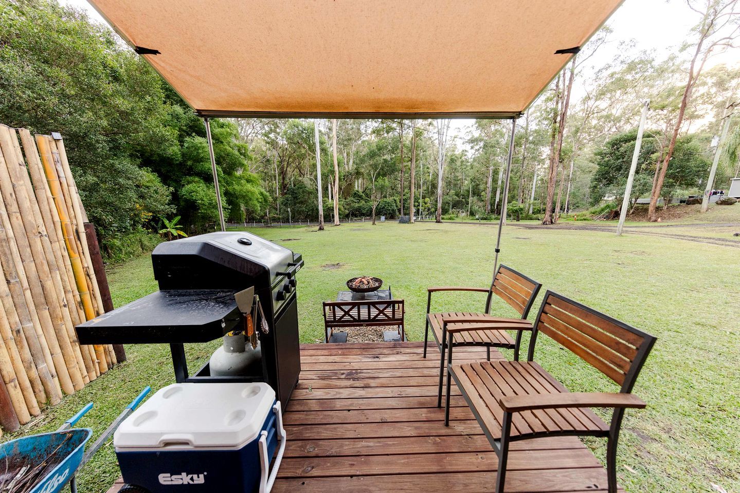 Un espace barbecue extérieur comprenant un gril, une table et deux chaises, le tout installé sur une terrasse en bois.