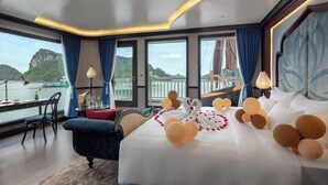 Un dormitorio lujoso con una cama grande, vistas a un barco y montañas, y un balcón con cortinas.