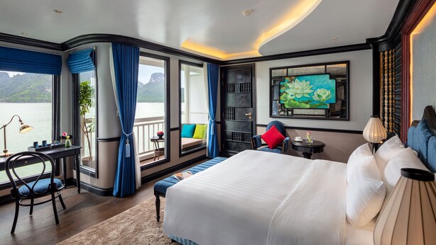 Un dormitorio con una cama grande, un escritorio y vistas a un cuerpo de agua.